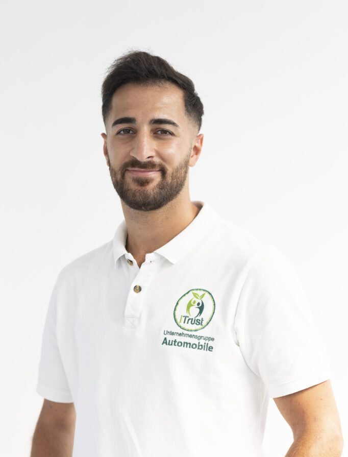 Portraitfoto vom Verkaufsleiter bei Autoankauf iTrust. In klassischer Pose und im weißen Poloshirt mit Unternehmenslogo.